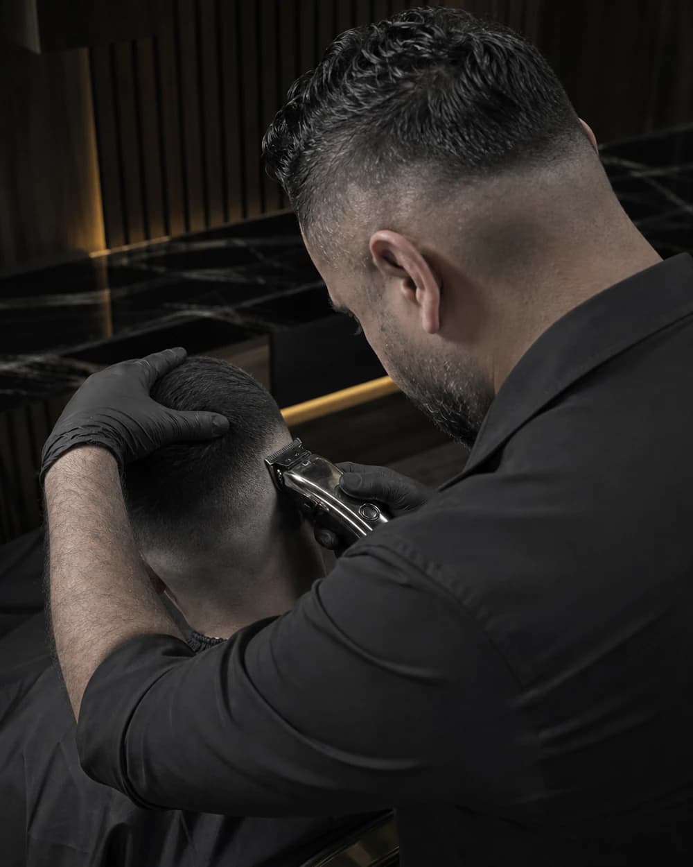 Ahmad Hussein von schräg hinten beim Ausarbeiten eines Fades mit der Haarschneidemaschine