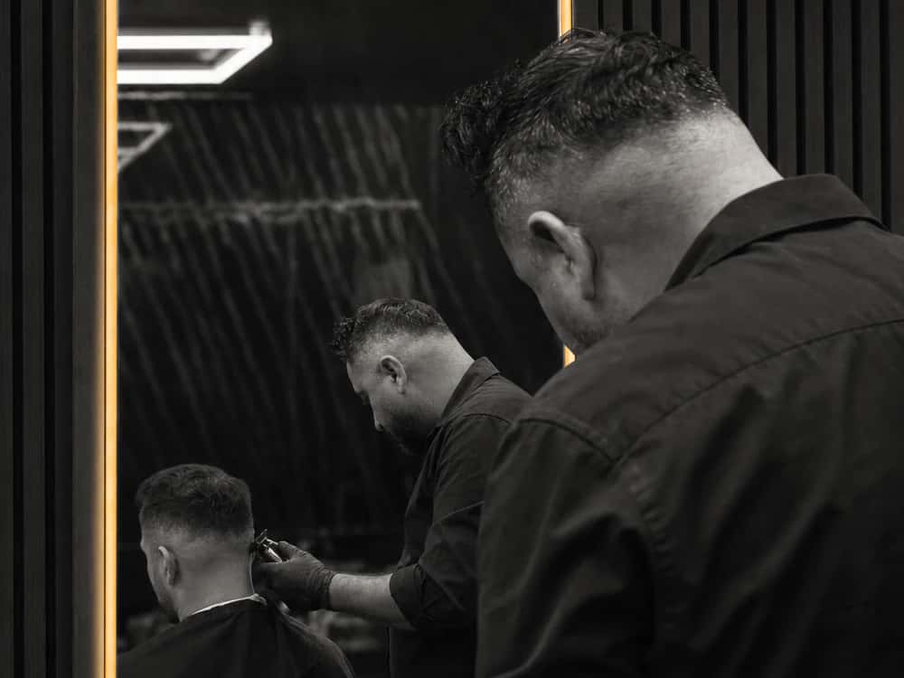 Barber in Neuss bei der Arbeit im beleuchteten Spiegel des NORF Barbershops